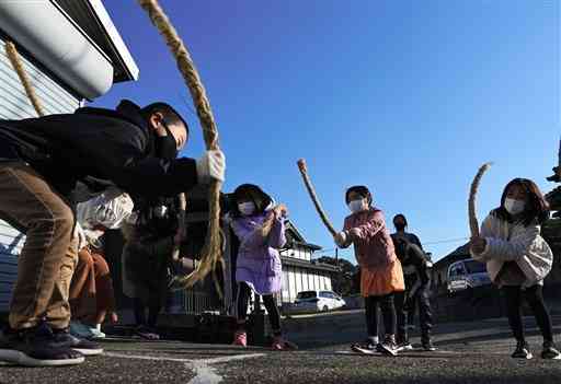 岩熊地区の民家の軒先でモグラ打ちをする子どもたち＝宇土市