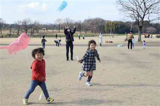 自分で作ったたこを高く揚げようと駆け回る子どもたち＝合志市