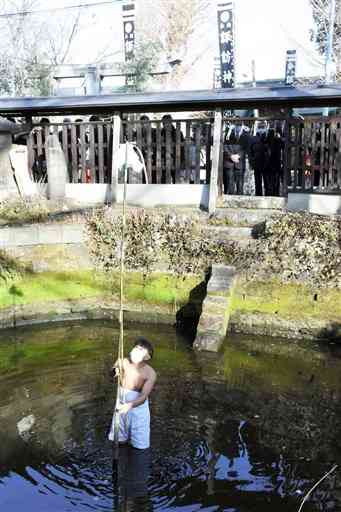 境内の池に入り、御幣を取り換えるさらし姿の氏子の男性＝玉名市