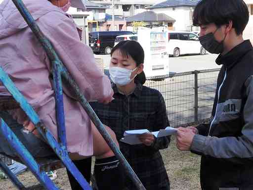 野外活動で子どもに紙飛行機の折り方を教える野尻有紗さん（中央）と下田大雅さん＝熊本市東区