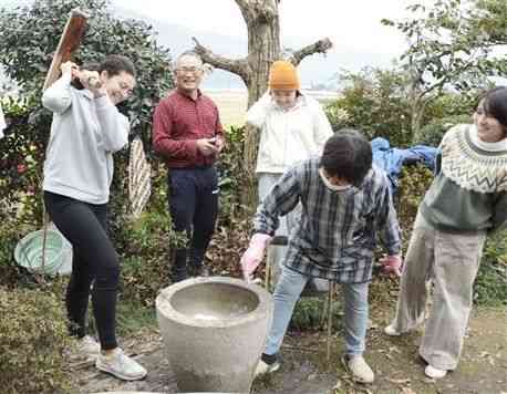 坂井米夫さん（左から２人目）の手ほどきで、餅つきを楽しむ留学生ら＝昨年１２月、八代市