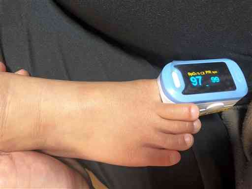 熊本市保健所から渡されたパルスオキシメーターで、長男の酸素飽和度を計測する女性（提供写真）