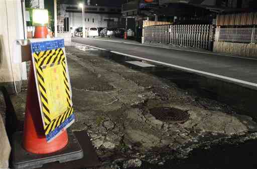 県内で最大震度５弱の地震発生した後、マンホールから水が漏れて水浸しになった道路沿いの敷地＝２２日午前５時１５分ごろ、熊本市中央区