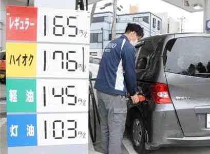 車に給油するガソリンスタンドの従業員。この日は「特売日」で、灯油以外を通常の２円引きで販売していた＝２７日、熊本市中央区