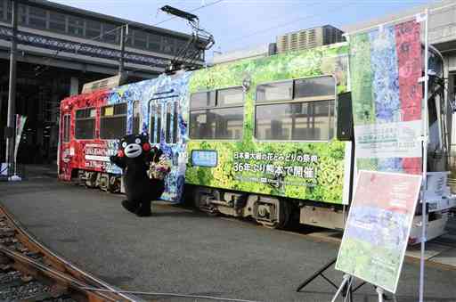 「全国都市緑化くまもとフェア」のラッピング電車前でＰＲするくまモン＝熊本市西区