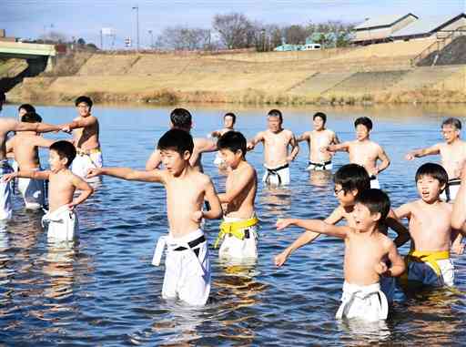 市空手道連盟の寒稽古で、菊池川に入り突きを繰り返す小中学生ら＝山鹿市