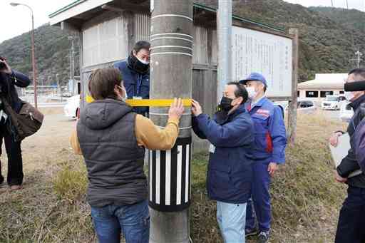 宅地かさ上げの高さの目印となるテープを電柱に貼り付ける国土交通省八代河川国道事務所の職員ら＝球磨村