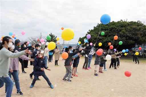 花の種を付けた風船を空に放つ富岡小の児童ら＝苓北町