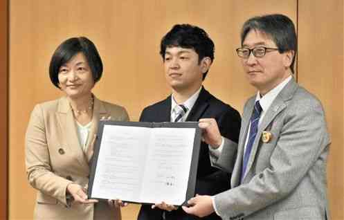 熊本市と立地協定を結んだハヴァナイスデイの市川俊介社長（中央）ら＝９日、県庁