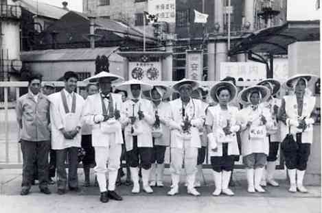 １９７１年のチッソ株主総会から戻り、水俣工場前で写真に納まる患者や支援者ら（鬼塚巌さん撮影、相思社提供）