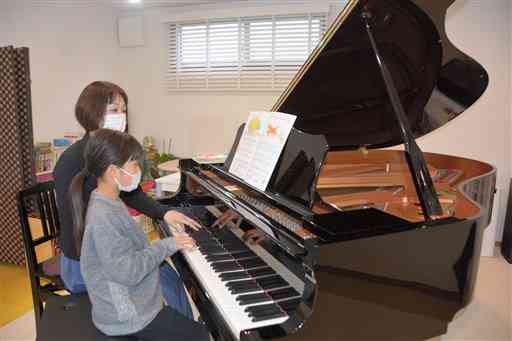 山野楽器が高野寺に寄贈したピアノで演奏する味岡眞理子さん（奥）とピアノ教室の生徒＝１日、人吉市