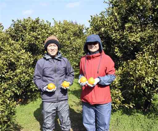 初収穫した不知火を手に笑顔の鍵田智嗣さん（左）、奈津美さん夫妻＝津奈木町