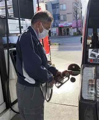 給油する肥後石油南熊本ＳＳの従業員。原油価格の高騰を受け、政府はガソリン補助金を引き上げる＝８日、熊本市中央区
