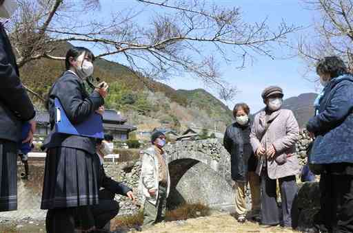 日本遺産などを巡るツアーで、笠松橋の案内をする八代東高の生徒（左）＝八代市東陽町