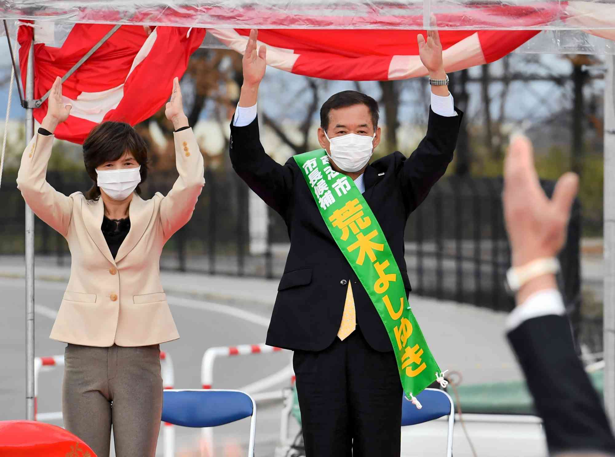 合志市長選で無投票での４選が決まり、支持者とともに万歳する荒木義行氏＝１３日午後５時１５分ごろ、同市竹迫の事務所近くの広場（石本智）