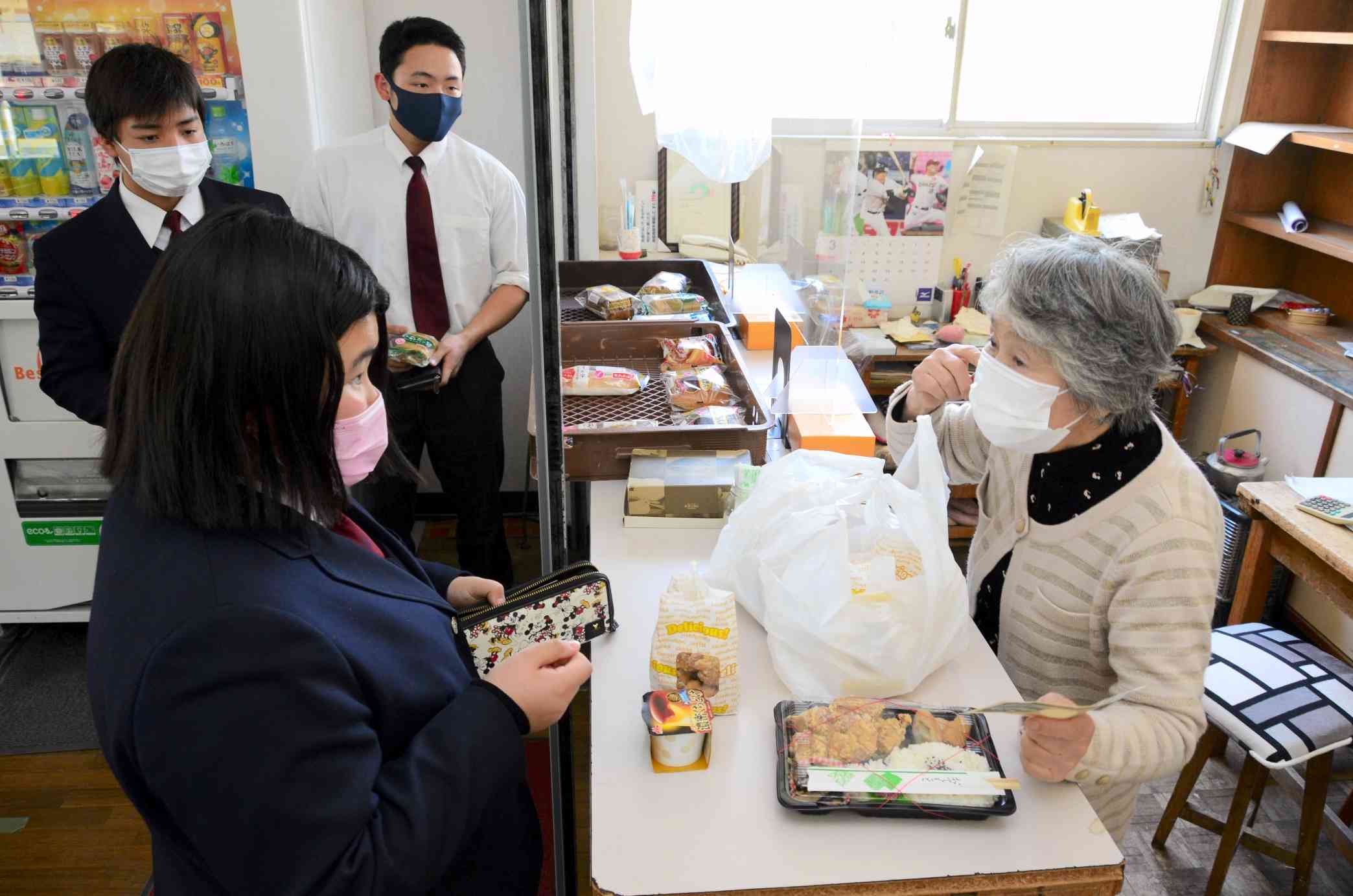 昼休みにパンや弁当を買い求める生徒の相手をする相馬和美さん（右）＝高森町