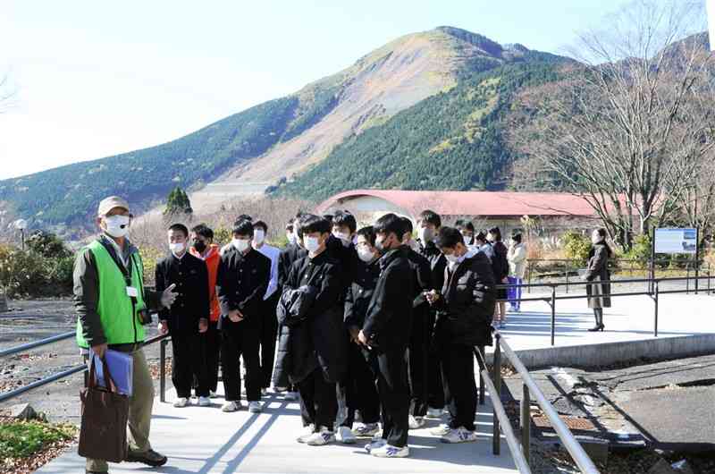 旧東海大阿蘇キャンパスで語り部の説明に耳を傾ける修学旅行で訪れた県外の中学生たち＝昨年１１月、南阿蘇村