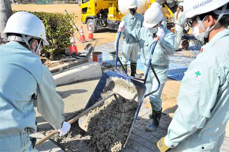 実習でスロープにコンクリートを敷き詰める玉名工高の生徒ら＝玉名市