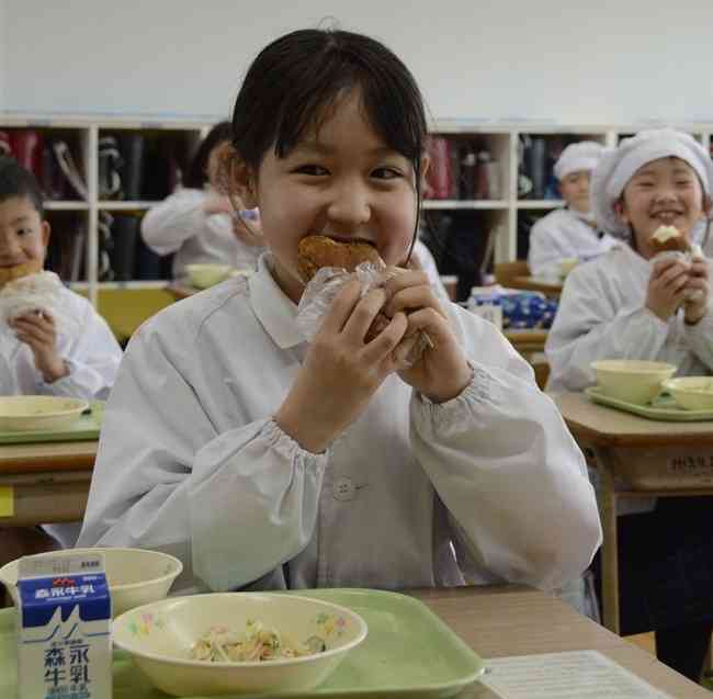 栽培した大豆から作ったきな粉を揚げパンにまぶして味わう、めのだけ小の３年生＝山鹿市