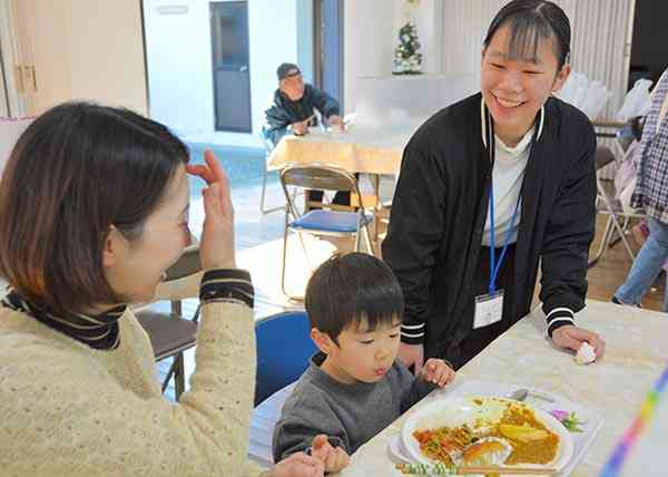 子ども食堂を訪れた親子と談笑するボランティアの小野萌華さん（右）＝熊本市中央区