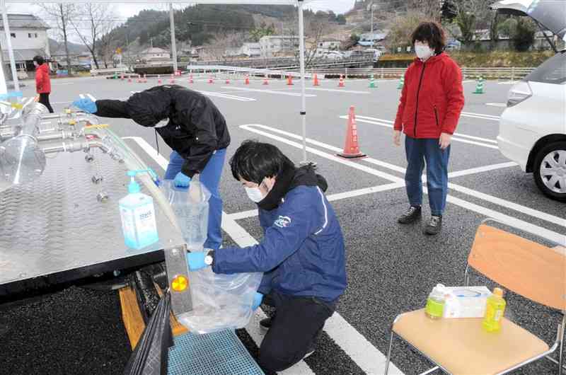 水を求めて訪れた住民（右）と、水をくむ町職員＝南小国町