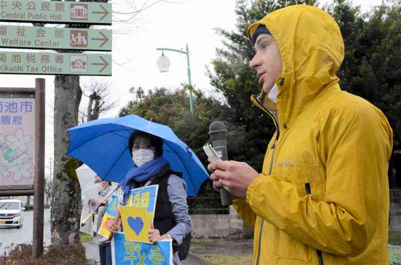 街頭に立ち、祖国ウクライナへの思いを訴えるブルシュク・オレフさん＝菊池市