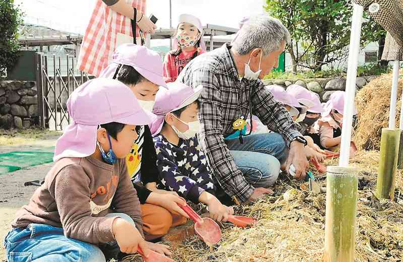 内田英雄さん（中央）の指導を受けながら土作りをする園児＝水俣市