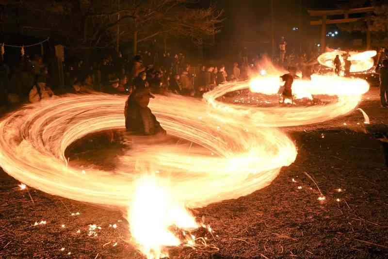 阿蘇神社参道で火の付いたカヤ束を豪快に回す氏子ら＝２０日夜、阿蘇市