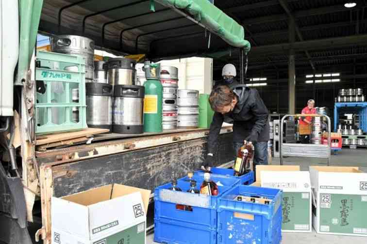 まん延防止等重点措置の解除を前に、飲食店に卸すビールなどをトラックの荷台に載せる寺本酒販の従業員ら＝２１日、熊本市南区