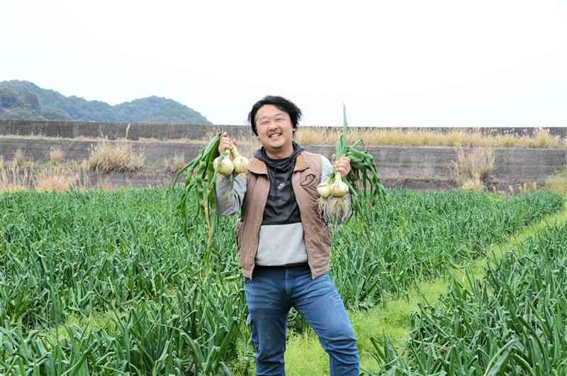 不知火海に面した農地5ヘクタールでサラダタマネギを栽培する釜博信さん。「芦北・水俣のタマネギのおいしさを全国に発信したい」と語る＝17日、芦北町