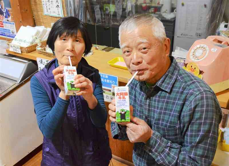 プレゼントされた牛乳を飲む温泉利用者＝菊池市