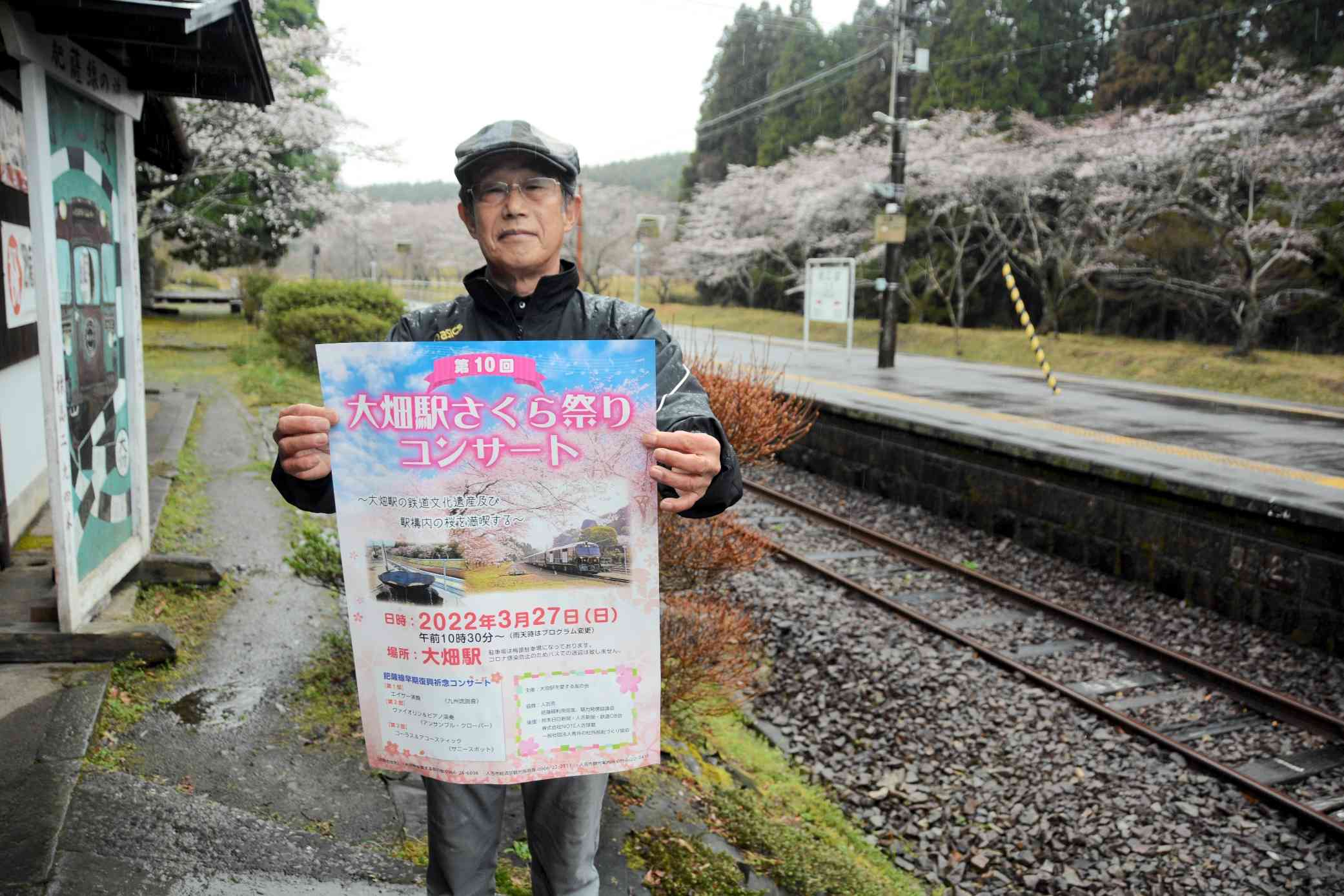 「さくら祭りコンサート」のポスターを持つ中村憲司さん＝人吉市