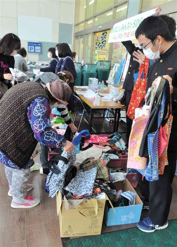 エコバッグや廃油せっけんなどを配布する小国中の生徒＝小国町