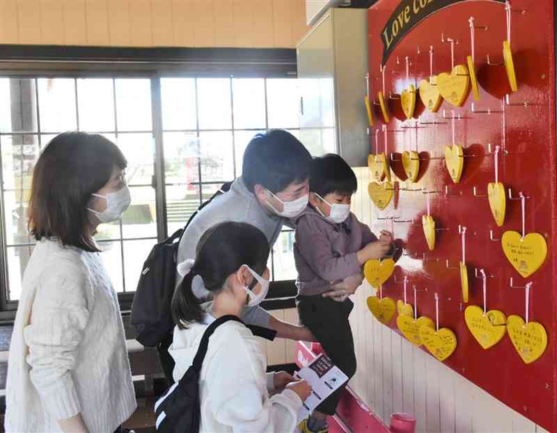 おかどめ幸福駅の駅舎に絵馬を飾る家族連れ＝あさぎり町