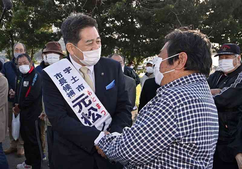 宇土市長に無投票で4選を決め、支持者らと握手する元松茂樹氏（左）＝27日午後5時10分ごろ、同市（後藤仁孝）