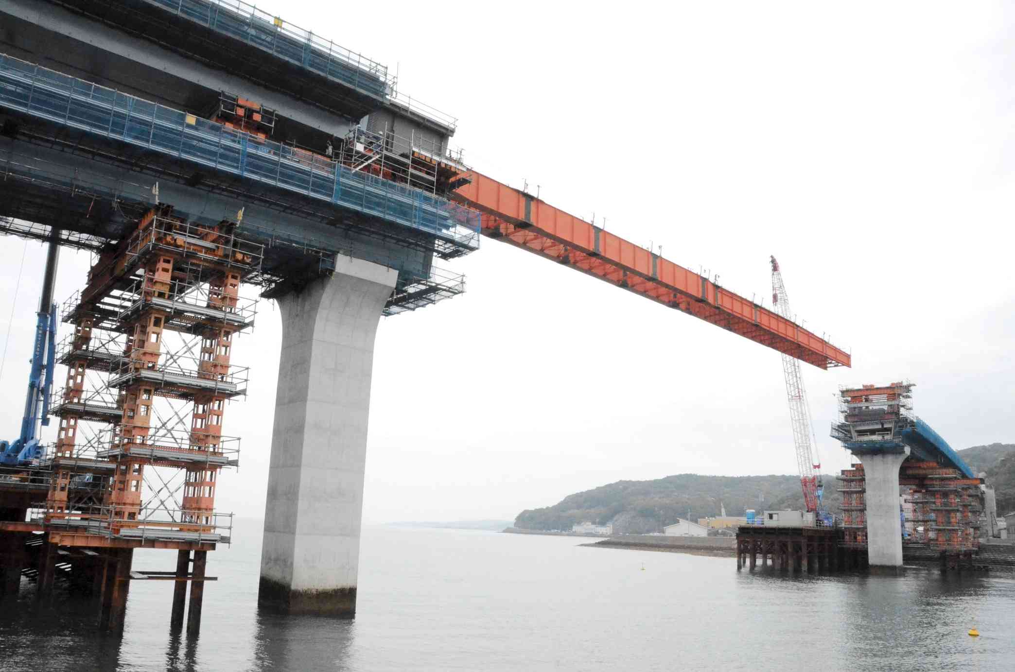 本渡瀬戸で架設が進む第2天草瀬戸大橋。天草下島側（左）の橋桁の上に載る橋桁を手延べ機を付けてスライドさせ、上島側（右）へ渡す＝天草市