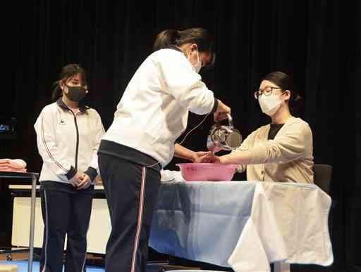 要介護者役の女性（右端）に声を掛けながら介助する高校生＝熊本市中央区