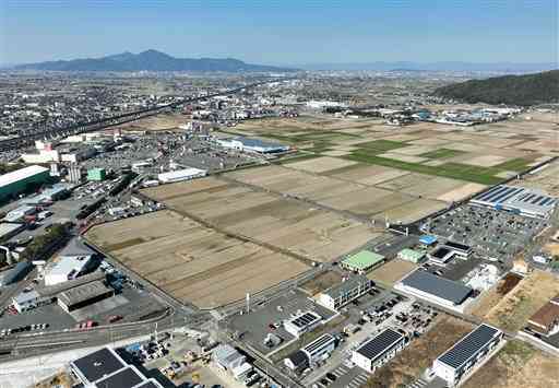 松原交差点付近に広がる農地。左を走る県道八代鏡宇土線沿いには宇土シティモールなどの商業施設が並ぶ。奥が熊本市方面＝２月２４日、宇土市（高見伸・池田祐介、小型無人機で撮影）