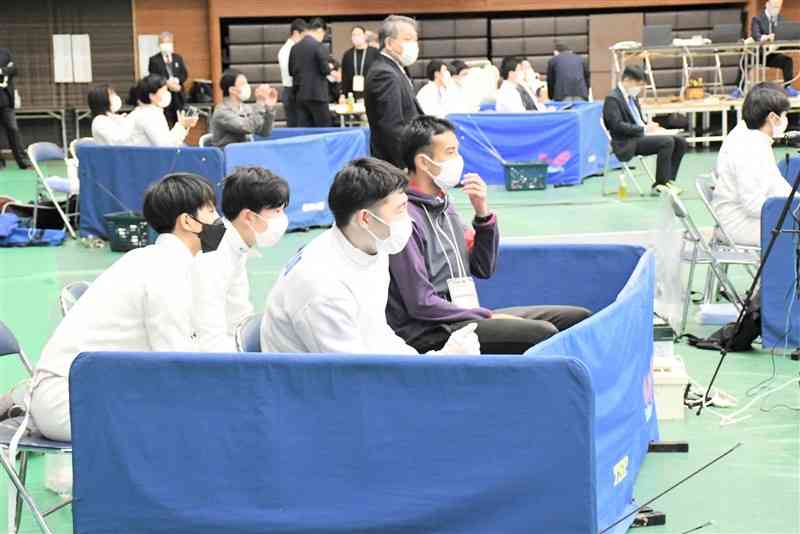 全国高校選抜フェンシング大会の男子団体エペ。マスク姿で仲間の試合を見守る選手たち＝3月27日、県立総合体育館