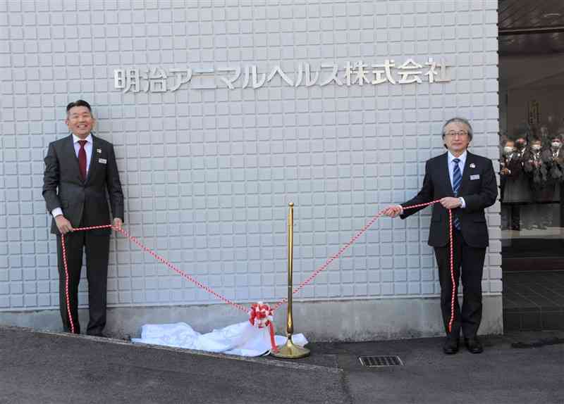 新会社「明治アニマルヘルス」の看板を除幕した同社の廣瀬和彦社長（左）ら＝1日、熊本市