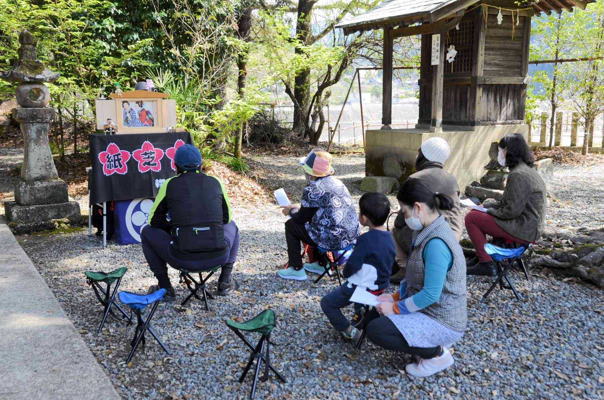 藤本五所神社の境内で紙芝居に見入る参加者＝八代市坂本町