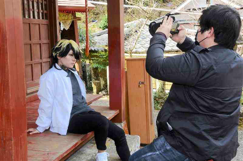 杖立温泉であったコスプレの撮影会で、お堂を背景に写真を撮影する参加者＝3月、小国町