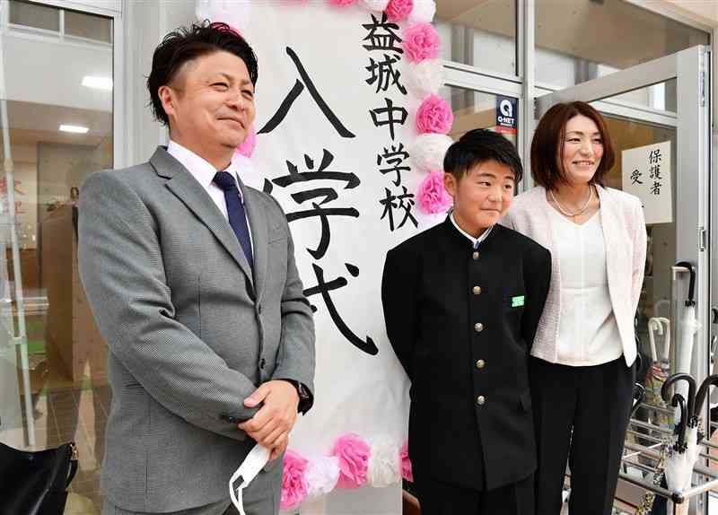 益城中の入学式で、父・修一さん（左）、母・香子さん（右）と記念撮影する市村龍馬さん＝11日午後、益城町（石本智）