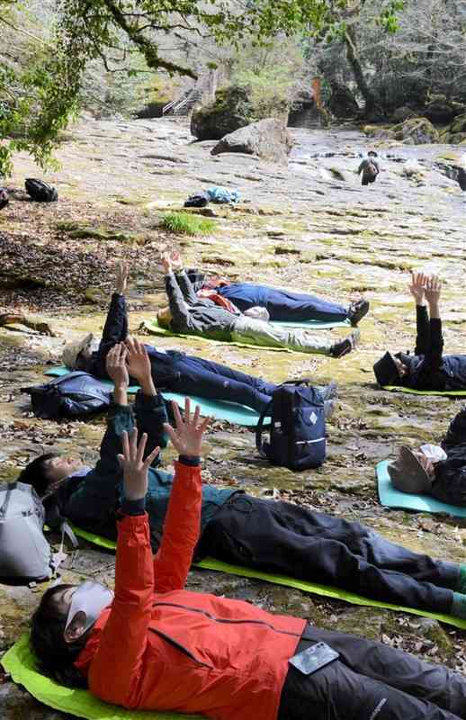 河原に横になって森林浴を体験する研修会の参加者＝菊池市