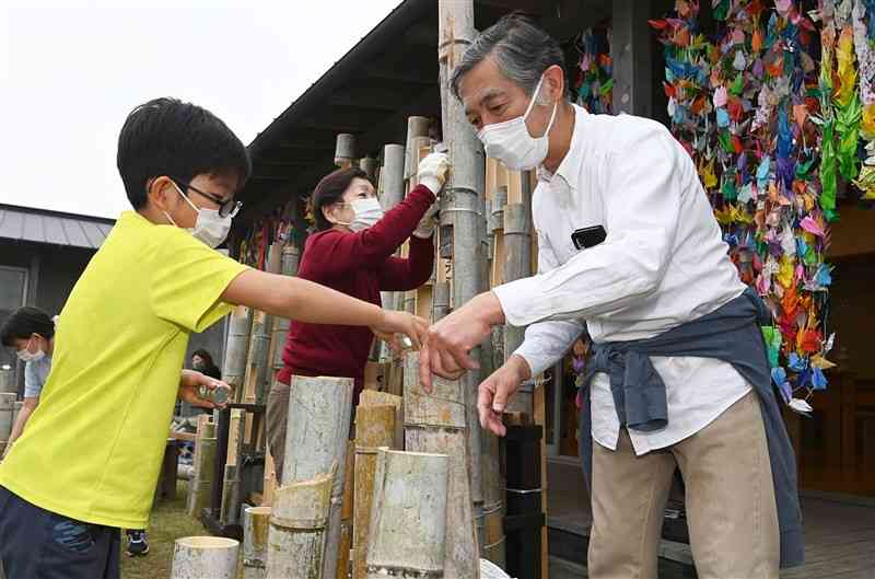 木山仮設団地の追悼行事で、竹灯ろうの準備をする橋本信一さん＝14日午後4時45分ごろ、