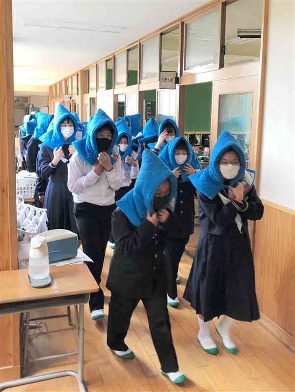 防災頭巾をかぶって避難する西原中の生徒ら＝西原村