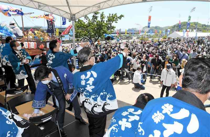 第50回牛深ハイヤ祭りの開幕記念式典で、お祝いのもちを投げる関係者＝天草市