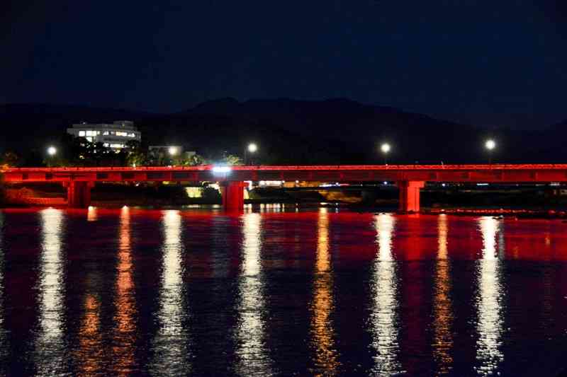 赤色にライトアップされた水の手橋＝人吉市