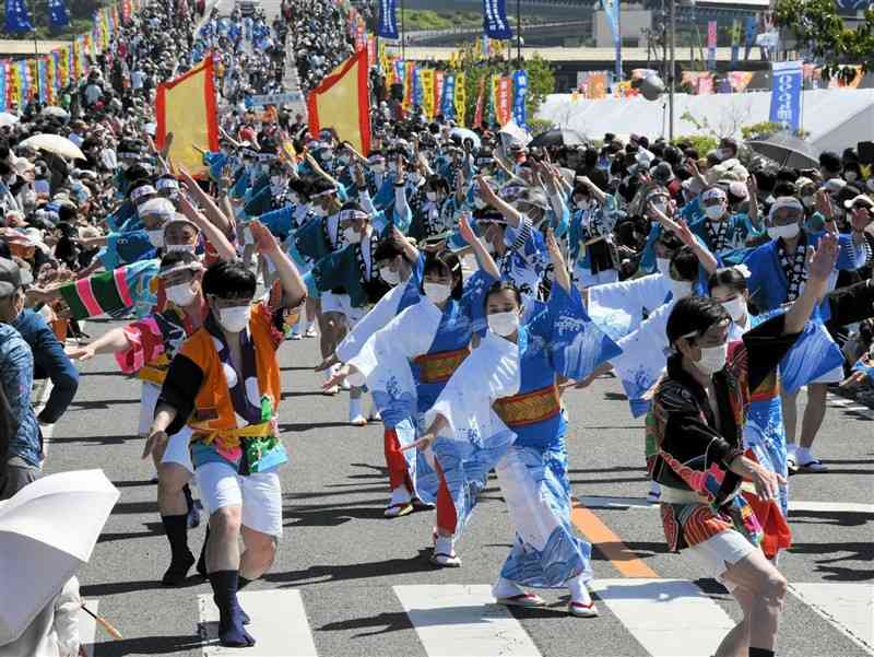 牛深ハイヤ大橋（後方）を下り、軽快に踊る参加者たち＝17日、天草市