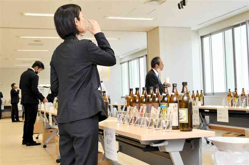 表彰式後の利き酒会で、出品された酒類の味や香りを確かめる来場者たち＝19日、熊本市西区